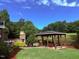 Backyard gazebo with stone fireplace overlooking a serene pond and lush, green landscape at 233 Hein Dr, Clayton, NC 27527