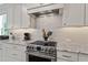 Gourmet kitchen features stainless steel stove, white cabinetry, granite countertops, and modern backsplash at 2409 Plowridge Rd, Fuquay Varina, NC 27526