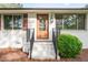 Inviting front entrance with a wood door, manicured shrubbery, and freshly painted white brick facade at 2712 Nc 57, Hillsborough, NC 27278