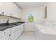 Bright laundry room featuring white cabinets, black countertops, stainless sink, and modern washer and dryer at 2712 Nc 57, Hillsborough, NC 27278