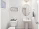 Bright half bathroom featuring a pedestal sink, an oval mirror, decorative sign and toilet at 277 Douglas Falls Dr, Wendell, NC 27591