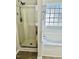 A bathroom with a glass door shower and a tub under a textured glass block window at 2902 Framer Ln, Durham, NC 27704