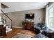 Cozy living room with hardwood floors, a decorative cabinet, and natural light from a bright window at 309 Cross Hill Ln, Holly Springs, NC 27540