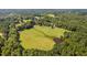 Aerial view of the property showing a large field and pond surrounded by lush trees at 3123 Brassfield Rd, Creedmoor, NC 27522