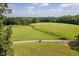 Aerial view of a verdant pasture, complemented by a scenic pond at 3123 Brassfield Rd, Creedmoor, NC 27522