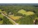 Expansive aerial view showcases property with lush fields, mature trees, and serene pond at 3123 Brassfield Rd, Creedmoor, NC 27522