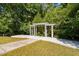 Lovely white arbor on a concrete platform with surrounding lush greenery creates a serene outdoor space at 3123 Brassfield Rd, Creedmoor, NC 27522
