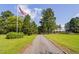 Long driveway leading to a charming home, surrounded by lush greenery and mature trees at 3123 Brassfield Rd, Creedmoor, NC 27522