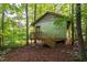 Cabin exterior featuring a rustic, corrugated metal design nestled in a lush, wooded setting at 3123 Brassfield Rd, Creedmoor, NC 27522