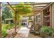 Inviting outdoor patio featuring overhead trellis, comfortable seating, lush garden views and adjacent parking at 3123 Brassfield Rd, Creedmoor, NC 27522