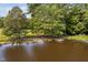 View of a serene pond with a floating dock, set among mature trees at 3123 Brassfield Rd, Creedmoor, NC 27522
