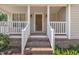 Inviting front porch with brick steps, white railings, columns, and a stained wood front door at 316 Waterford Dr, Clayton, NC 27520