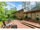 Brick patio with outdoor seating and a fire pit, surrounded by lush landscaping and mature trees at 4017 Huckleberry Dr, Raleigh, NC 27612