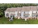 Aerial view of townhome backyards featuring well-maintained lawns and private patios with stairs leading to green space at 407 Whitehall Ct, Clayton, NC 27520