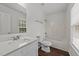 Bright bathroom featuring white vanity with chrome faucet, matching toilet, and shower at 407 Whitehall Ct, Clayton, NC 27520