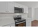 Modern kitchen features stainless steel appliances, white cabinetry, and quartz countertops at 407 Whitehall Ct, Clayton, NC 27520