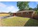 View of the brick home exterior with a covered patio, lawn, and partial fence on a sunny day at 464 Camp Rd, Burlington, NC 27217