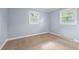 A simple bedroom with neutral carpet, two windows, and light blue painted walls at 464 Camp Rd, Burlington, NC 27217