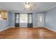 Living room with hardwood floors, ceiling fan, front door, window with curtains, and light blue walls at 464 Camp Rd, Burlington, NC 27217