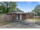 Rear view of a red brick house, fenced yard, and carport on a sunny day at 464 Camp Rd, Burlington, NC 27217