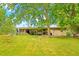 View of the home's rear exterior and covered patio, surrounded by a sloping, well-maintained lawn at 509 Stokes Rd, Graham, NC 27253