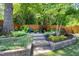 Beautifully landscaped backyard patio area with stone pathway, retaining wall, and Adirondack chairs for relaxing at 512 Page St, Cary, NC 27511
