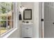 Powder room with vanity, dark framed mirror and view of yard through the window at 5237 Christian Light Rd, Fuquay Varina, NC 27526