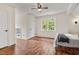 Bright bedroom with hardwood floors, ceiling fan, and a window view of lush greenery at 5237 Christian Light Rd, Fuquay Varina, NC 27526