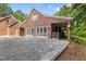 Brick home featuring a gravel parking area, covered patio, and lush foliage in the background at 5237 Christian Light Rd, Fuquay Varina, NC 27526