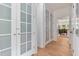 Hallway with frosted glass closet doors, hardwood floors, and leading to the dining room and kitchen at 5237 Christian Light Rd, Fuquay Varina, NC 27526