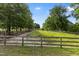 Expansive pasture with a charming wooden fence, lush greenery, and a clear blue sky at 5237 Christian Light Rd, Fuquay Varina, NC 27526