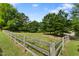 Expansive fenced pasture with vibrant green grass, mature trees, and a classic wooden fence at 5237 Christian Light Rd, Fuquay Varina, NC 27526