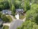 Aerial view of a two story brick home with a black roof surrounded by lush landscaping and mature trees at 6 Beltre Ct, Durham, NC 27705