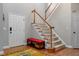 The entryway features hardwood floors, a staircase, a red bench, a white front door, and neutral colored walls at 6 Beltre Ct, Durham, NC 27705