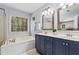 Well-lit main bathroom featuring double sinks, a soaking tub under a bright window, and ample counter space at 6 Beltre Ct, Durham, NC 27705