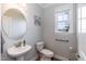 Cozy powder room featuring a pedestal sink, toilet, wall art and window offering natural light at 76 Freewill Pl, Raleigh, NC 27603