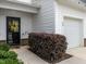 Close-up of townhome's front entrance with black door, white siding, and landscaped bushes at 80 Willow Green Dr, Clayton, NC 27527