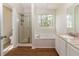 Well-lit bathroom with separate shower and tub, granite countertops, and wood floors at 805 Penncross Dr, Raleigh, NC 27610
