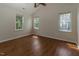 Spacious bedroom featuring wood floors, ceiling fan, and plenty of natural light from three windows at 805 Penncross Dr, Raleigh, NC 27610