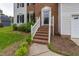 Charming front entrance with brick steps, white railings, and tidy landscaping at 805 Penncross Dr, Raleigh, NC 27610