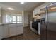 Modern kitchen boasts stainless steel refrigerator, range, white cabinets and countertops, and seamless wood-look flooring at 805 Penncross Dr, Raleigh, NC 27610