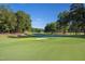 Scenic view of a lush green golf course, sand trap, and flag under a clear blue sky, surrounded by mature trees at 81502 Alexander, Chapel Hill, NC 27517