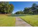 Scenic view of a lush green golf course with a paved cart path winding through towering trees under a clear blue sky at 81502 Alexander, Chapel Hill, NC 27517