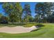 Scenic view of a pristine sand bunker surrounded by a lush green golf course and mature trees under a clear blue sky at 81502 Alexander, Chapel Hill, NC 27517