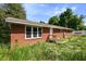 A cozy one-story brick house featuring large windows and a well-maintained roof, with a PODS container nearby at 995 Shawtown Rd, Lillington, NC 27546