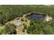 Aerial view of a home with a pond and outbuildings nestled in a wooded landscape at 1131 Pulley Gordon Rd, Zebulon, NC 27597
