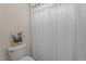 Bathroom with a toilet topped with floral decor next to a shower enclosed by a gray and white curtain at 1131 Pulley Gordon Rd, Zebulon, NC 27597