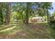 View of a large backyard with mature trees, with a glimpse of the home and its wooden deck at 1208 W Murray Ave, Durham, NC 27704