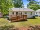 The backyard features a wooden deck with ramp and a spacious lawn, trash cans, and partial shade at 1208 W Murray Ave, Durham, NC 27704