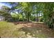 A spacious backyard with a mix of grass and shaded areas, partially enclosed by a fence at 1208 W Murray Ave, Durham, NC 27704